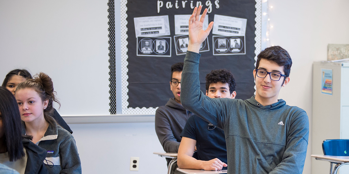 Student raising their hand in a classroom setting