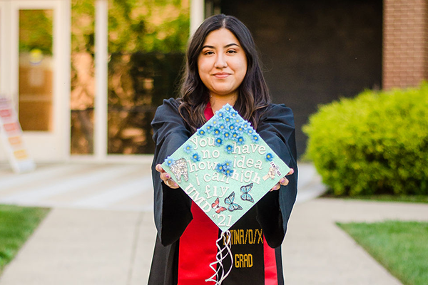 Olga Cordero An ACES Graduate Holding Up Her Decorated Graduation Cap
